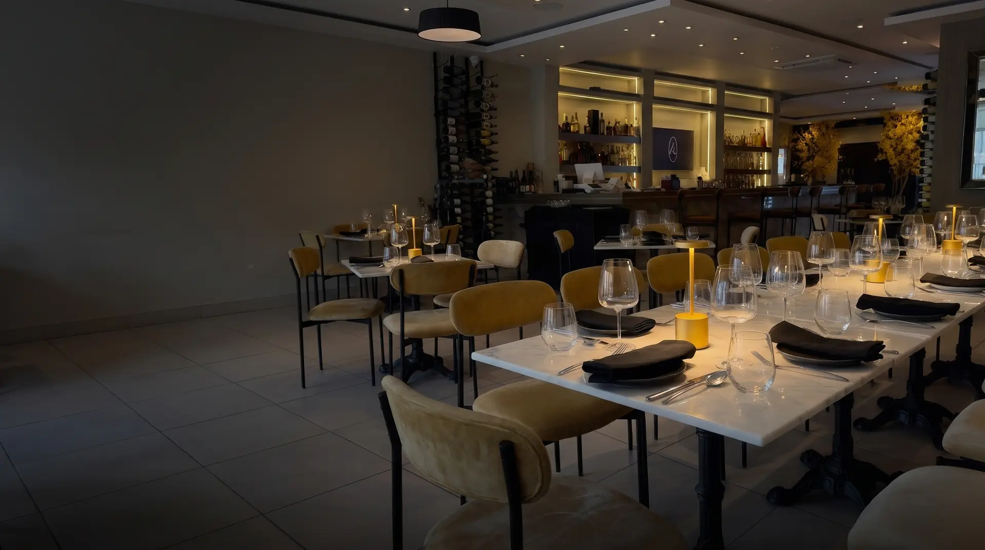 Mesa larga montada para evento en el salón de Mil Estrellas, con lámparas doradas y la barra al fondo