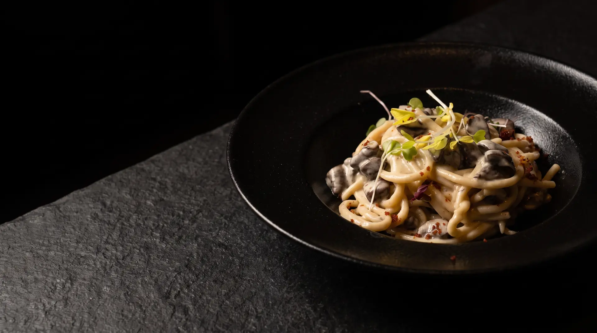 Pasta trufada con setas shiitake y trufa fresca en plato negro